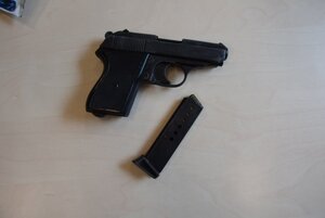 leżąca na biurku zabezpieczona do sprawy jednostka broni gazowej, obok magazynek z nabitą amunicją gazową