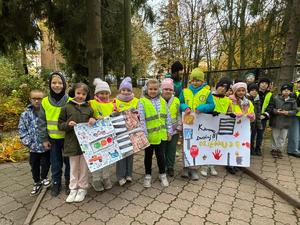 Dzieci w kamizelkach odblaskowych trzymające plakaty