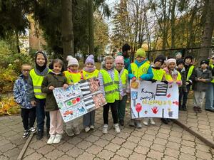Dzieci w kamizelkach odblaskowych trzymające plakaty