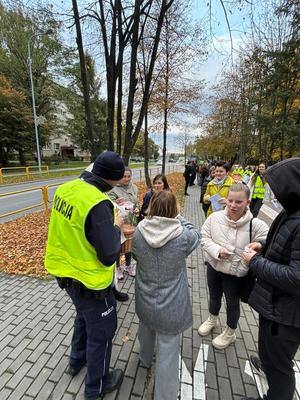 Policjant w kamizelce odblaskowe i grupa osób