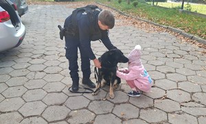 wychowanka ośrodka głaszcząc policyjnego psa, obok przewodnik psa