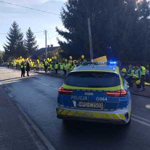 oznakowany radiowóz obok pochód dzieci z odblaskami i balonami