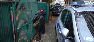 Polcijant rozmawia z meżczyzną przez bramę