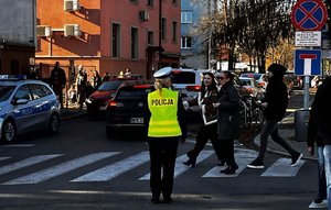 policjantka przepuszcza pieszych przez przejście dla pieszych