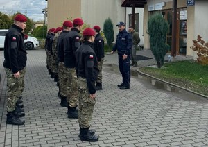 Uczniowie klasy mundurowej stojący w dwuszeregu, przed nimi umundurowany policjant
