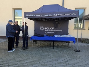 Namiot policyjne a przy nim policjantka i policjant oraz mężczyzna