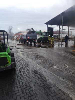 umundurowani strażacy obok spalony budynek i sprzęt rolniczy