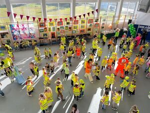 Dzieci w kamizelkach odblaskowych bawią się na sali