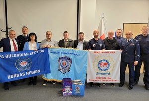 Na zdjęciu mężczyźni w strojach cywilnych, umundurowani policjanci oraz kobieta. W rekach trzymają trzy flagi.