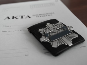 blacha policyjna położona na teczkę na akta postępowania karnego