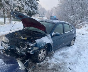 Kolizja drogowa dwóch samochodów osobowych, na drugim planie oznakowany radiowóz