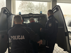 Policjanci prowadzą zatrzymanego do radiowozu