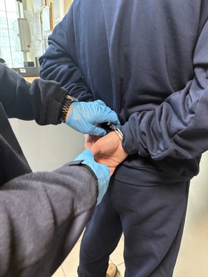 policjant zakłada zatrzymanemu kajdanki