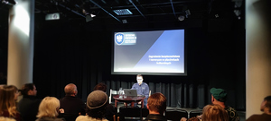 policjant prowadzący szkolenie, telebim w tle