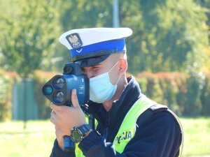 Policjant ruchu drogowego trzyma w ręku ręczny miernik prędkości