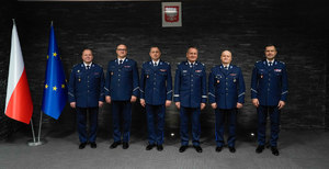 wspólne zdjęcie awansowanych z komendantami wojewódzkimi z godłem i flagami