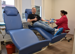 Policjant siedzący na fotelu, podczas pobierania krwi oraz pielęgniarka