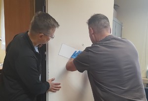 Technik kryminalistyki prezentuje aktorowi zdejmowanie śladów z drzwi