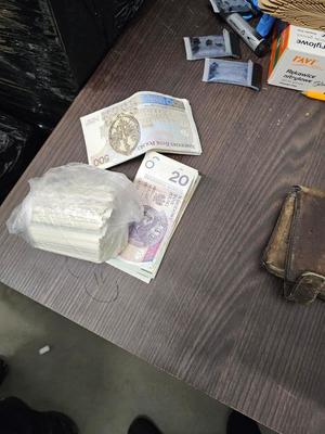 Na stoliku leży portfel i plik banknotów