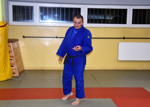 Trener Grzegorz Maj w stroju sportowym. W ręce trzyma stoper