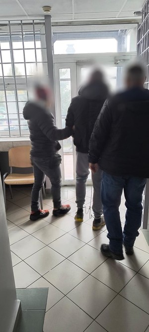 Mezczyzna prowadzony w kajdankach