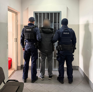 Policjanci prowadzą mężczyznę zakutego w kajdanki