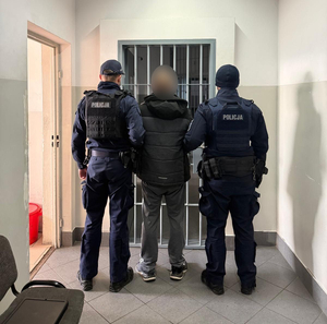 Policjanci prowadzą mężczyznę zakutego w kajdanki