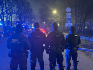 czterech umundurowanych policjantów biorących udział w zabezpieczeniu meczu stojących tyłem do zdjęcia.