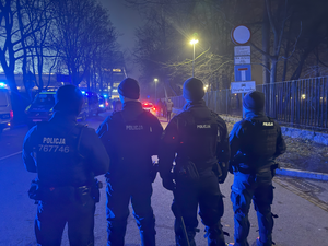 czterech umundurowanych policjantów biorących udział w zabezpieczeniu meczu stojących tyłem do zdjęcia.