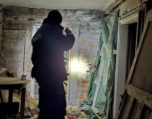 Umundurowany policjant sprawdzający pomieszczenia pustostanu.