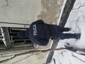 Umundurowany policjant stojący tyłem zerkający przez okno