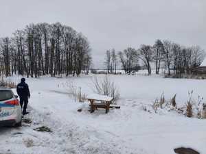 Umundurowany policjant kontrolujący teren zamarzniętego zbiornika wodnego