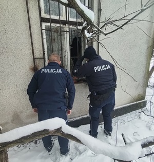 Dwóch policjantów zerkających przez rozbite okno