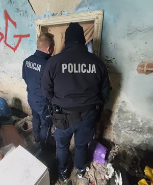Dwóch umundurowanych policjantów zerkających przez drzwi