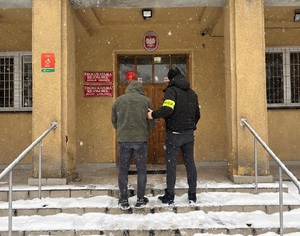 nieumundurowany policjant prowadzi zatrzymanego meżczyznę do prokuratury