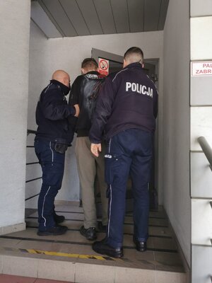 dwóch policjantów wprowadza zatrzymanego do komendy