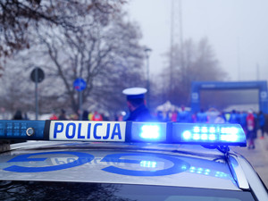 belka świetlna radiowozu oraz policjant ruchu drogowego. w tle start biegu.