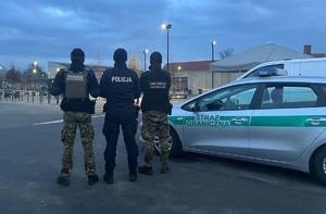 6 KPP Oświęcim. Zabezpieczenie 81. rocznicy wyzwolenia Auschwitz-Birkenau   policjant i strażnicy graniczni przy radiowozie