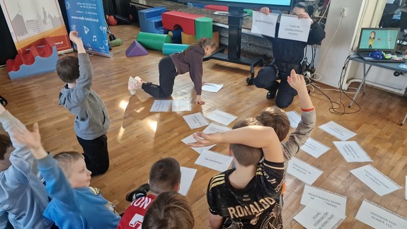 dzieci zgłaszają się chcąc odpowiedzieć na zadane przez policjantkę pytania