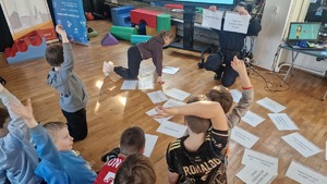 dzieci zgłaszają się chcąc odpowiedzieć na zadane przez policjantkę pytania