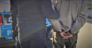 KPP Oświęcim. Policjant przy radiowozie z zatrzymanym przykład