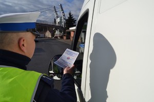 Policjant wręczający broszurkę.