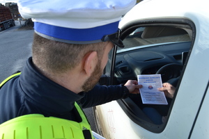 Policjant wręczający broszurkę