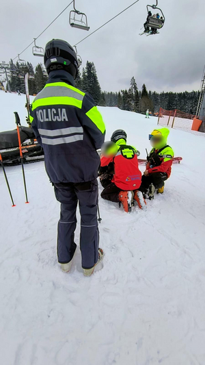 policjant z patrolu narciarskiego zabezpiecza działania ratowników