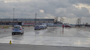 Radiowozy policyjne poruszające się po płycie poślizgowej, na budynku napis MOTO PARK KRAKÓW