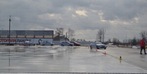 Radiowozy policyjne poruszające się po płycie poślizgowej, pod nadzorem instruktora techniki jazdy.