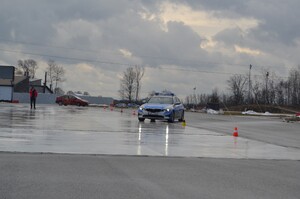 Radiowóz policyjny za nim czerwony samochód jeżdżą po płycie poślizgowej