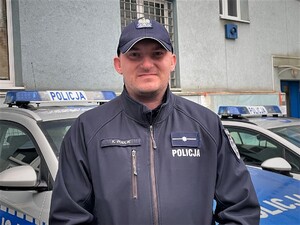 dzielnicowy młodszy aspirant Krzysztof Pudlik na tle radiowozu