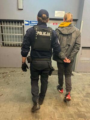 policjant w mundurze prowadzi zatrzymengo do izby zatrzymań