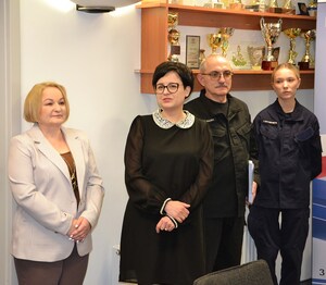 dyrektor szkoły przemawia, obok nauczyciele i uczennica